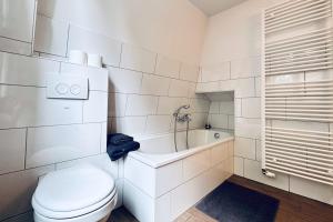 a white bathroom with a toilet and a bath tub at Der Stader Hafenblick in Stade