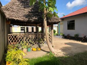 巴加莫約的住宿－BeSwahilid B & B，茅草屋顶和棕榈树的房子