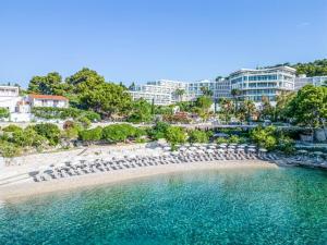 - une plage avec des parasols et des chaises en face d'un complexe dans l'établissement Amfora Hvar Grand Beach Resort, à Hvar