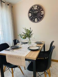 a dining room table with a clock on the wall at El Apartamento de la Colegiata in Vigo