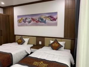 a hotel room with two beds and a painting on the wall at Anika Hotel in Ha Long
