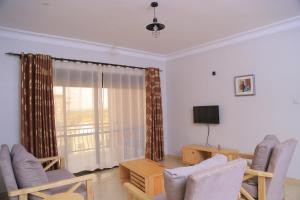ein Wohnzimmer mit Stühlen, einem Tisch und einem TV in der Unterkunft The Junction Apartments in Mbarara