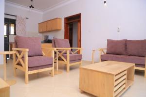 ein Wohnzimmer mit lila Stühlen und einem Couchtisch in der Unterkunft The Junction Apartments in Mbarara