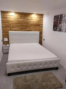 - un grand lit blanc dans une chambre avec un tapis dans l'établissement Apartament Syrenka przy jeziorze Czos, à Mrągowo