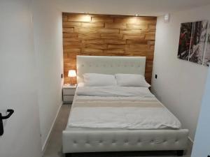 a white bed in a room with a wooden wall at Apartament Syrenka przy jeziorze Czos in Mrągowo