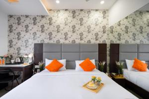 a bedroom with a bed with orange pillows and a desk at Hotel Marigold Atnest Gachibowli - A Business Hotel in Gachibowli +18 photos