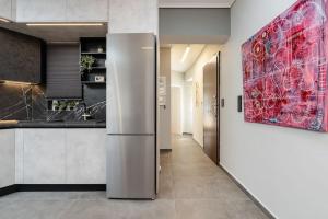 a stainless steel refrigerator in a kitchen with a red painting at Stylish 1BD Apt in Elliniko in Athens