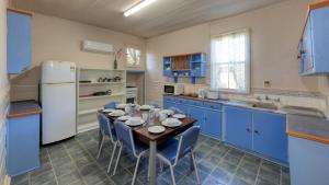 uma cozinha com armários azuis e uma mesa com cadeiras em Charles Rasp Motor Inn & Cottages em Broken Hill