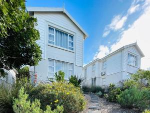 a white house with a garden in front of it at Pinnacle Point Golf Estate - Golf Lodge 114 in Mossel Bay