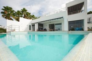 a swimming pool in front of a house at Casa Rosa de los Vientos, al lado de la playa in Sant Josep de Sa Talaia
