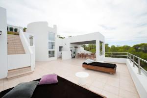 een wit huis met een bed op een balkon bij Casa Rosa de los Vientos, al lado de la playa in San Jose de sa Talaia