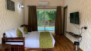 ein Schlafzimmer mit einem Bett und ein Fenster mit einem Pool in der Unterkunft Bhil's Kabeela Resort & Spa Kanha in Dhanwār