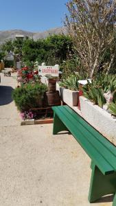 a green bench sitting in front of a garden at Apartments Vesna in Pag