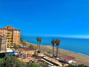 einen Strand mit Palmen und einem Gebäude und dem Meer in der Unterkunft Apartamento Vistas al mar in Algarrobo-Costa