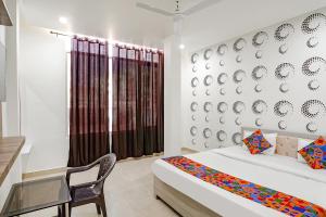 a bedroom with a bed and a chair and a window at FabHotel Siddhi in Varanasi