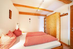 レージアにあるMühlanderhof Apt Klopairspitzeのベッドルーム1室(ベッド1台に赤と白の枕2つ付)