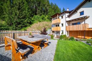 a backyard with a wooden table and benches at Mühlanderhof Apt Klopairspitze in Resia