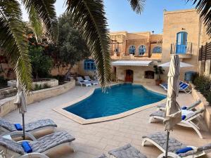 a swimming pool with lounge chairs and a house at Ta' Ġilarda Boutique Living in Birbuba