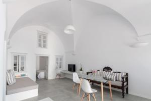 Sala de estar blanca con sofá y mesa en Evmenia Luxury Cave Villa, en Oia