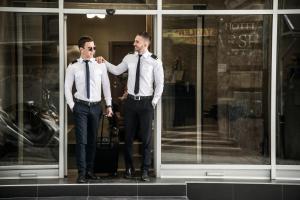two men in ties standing in front of a window at FLOK Old Town - Hotel Marshal in Belgrade