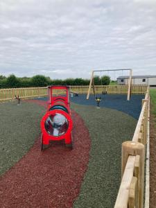 a playground with a red train on a playground at Chapel Fields Holiday Park in Chapel Saint Leonards
