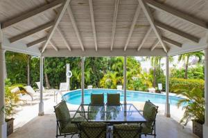 een patio met een tafel en stoelen en een zwembad bij Palm Ridge 2A Heaven Scent, Royal Westmoreland by Barbados Sothebys International Realty in Saint James
