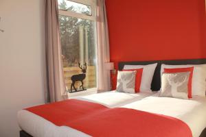 1 dormitorio con 1 cama con pared roja y ventana en Apartments Bommels en Vierhouten
