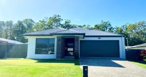 a house with a garage in a yard at Plantation Retreat 4 Bedroom Modern Home in Landsborough