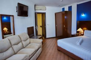une chambre d'hôtel avec un canapé et un lit dans l'établissement Central Hotel Tana, à Antananarivo