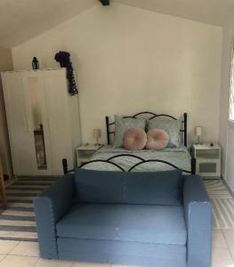 een blauwe bank in een slaapkamer met een bed bij Un Studio dans un endroit tranquille in Roquefort-les-Pins