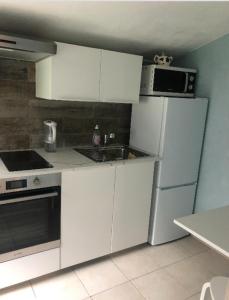 een keuken met witte kasten, een magnetron en een koelkast bij Un Studio dans un endroit tranquille in Roquefort-les-Pins