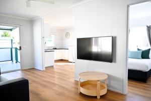 sala de estar con TV de pantalla plana grande en la pared en Glen Villa Resort en Byron Bay