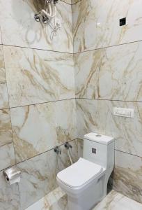 uma casa de banho com um WC branco e paredes em mármore em THE R MOTEL Phagwara City -- Full Privacy & Security -- Family,Corporate,Couples Favorite em Phagwāra