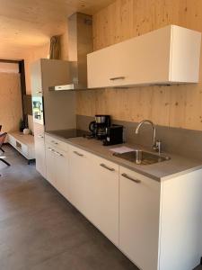 a kitchen with white cabinets and a sink at Luxe vakantielodge in Callantsoog aan zee in Callantsoog