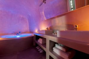 La salle de bains est pourvue d'une baignoire, de 2 lavabos et d'une baignoire. dans l'établissement Evmenia Luxury Cave Villa, à Oia