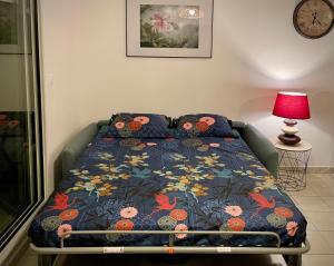 a bed with a blue comforter with flowers on it at Appartement lumineux rénové à neuf in Saint-Pierre