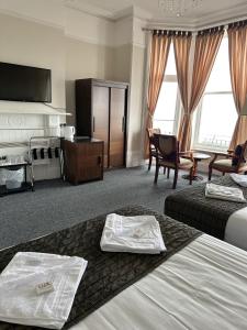 a hotel room with two beds and a television at Glastonbury Hotel in Eastbourne