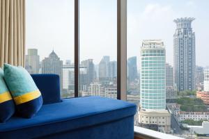 niebieskim krzesłem w pokoju z widokiem na miasto w obiekcie Renaissance Shanghai Yu Garden Hotel w Szanghaju