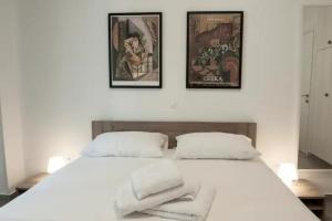 a bedroom with a white bed with three pictures on the wall at SYNTAGMA VOULIS STREET MODERN APARTMENT in Athens