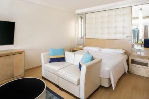 a bedroom with a bed and a chair and a tv at Renaissance Shanghai Yu Garden Hotel in Shanghai