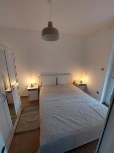 1 dormitorio con 1 cama blanca y 2 mesitas de noche en Fűzliget Wave, en Balatonfűzfő