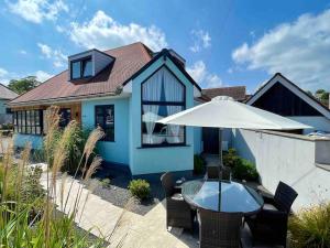 Casa azul con mesa y sombrilla en Torquay holiday home near the sea en Torquay