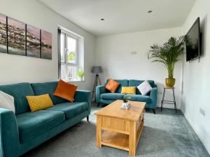 a living room with two blue couches and a table at Torquay holiday home near the sea in Torquay