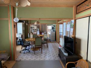 a kitchen and dining room with a table and a television at 余呉の里山-ランプの宿-さくら in Nagahama