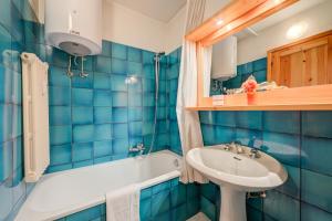 a blue tiled bathroom with a sink and a tub at Appartamento La Marmotta Mountain Retreat - Happy Rentals in Claviere +16 photos