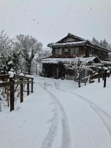 a house is covered in snow in front of a road at 余呉の里山-ランプの宿-さくら in Nagahama +12 photos