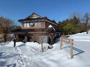 Ein Mann steht im Schnee vor einem Haus in der Unterkunft 余呉の里山-ランプの宿-さくら in Nagahama