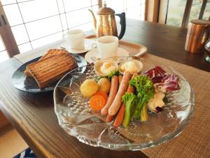 長濱的住宿－余呉の里山-ランプの宿-さくら，桌上装有蔬菜和面包的玻璃盘