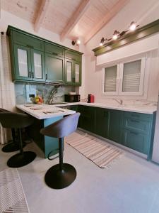 a kitchen with green cabinets and a bar stool at The Old Stables Apartment in Vátos