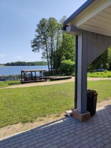 a porch of a house with a picnic table next to the water at Zvaigznītes in Aglona